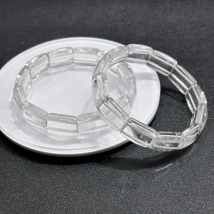 Clear quartz square tablet bracelets crossed on dark surface, handmade aesthetic jewelry for daily wear