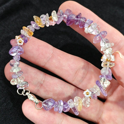 Hand holding a delicate non elastic amethyst and citrine chip stone wire wristband displaying metal clasp fastening