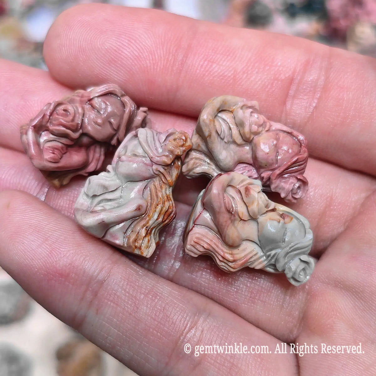 Close up view of natural multi color Alxa agate floral goddess carved statues resting on hand highlighting smooth finish
