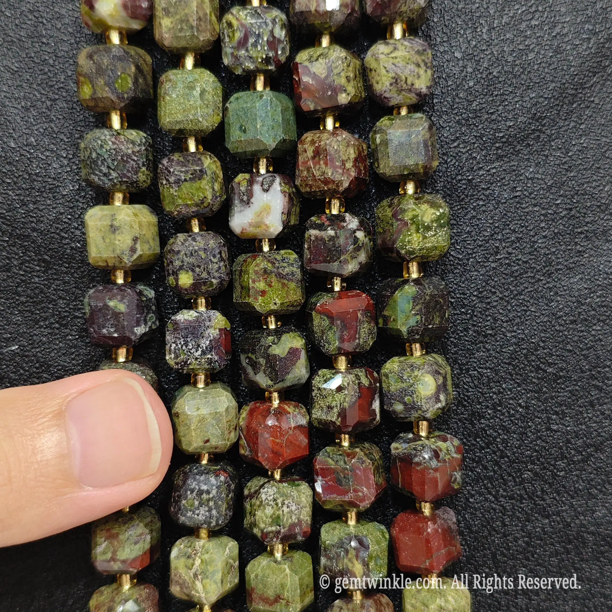 Multiple parallel strands of natural dragon blood jasper soft-tumbled cube beads viewed from distance