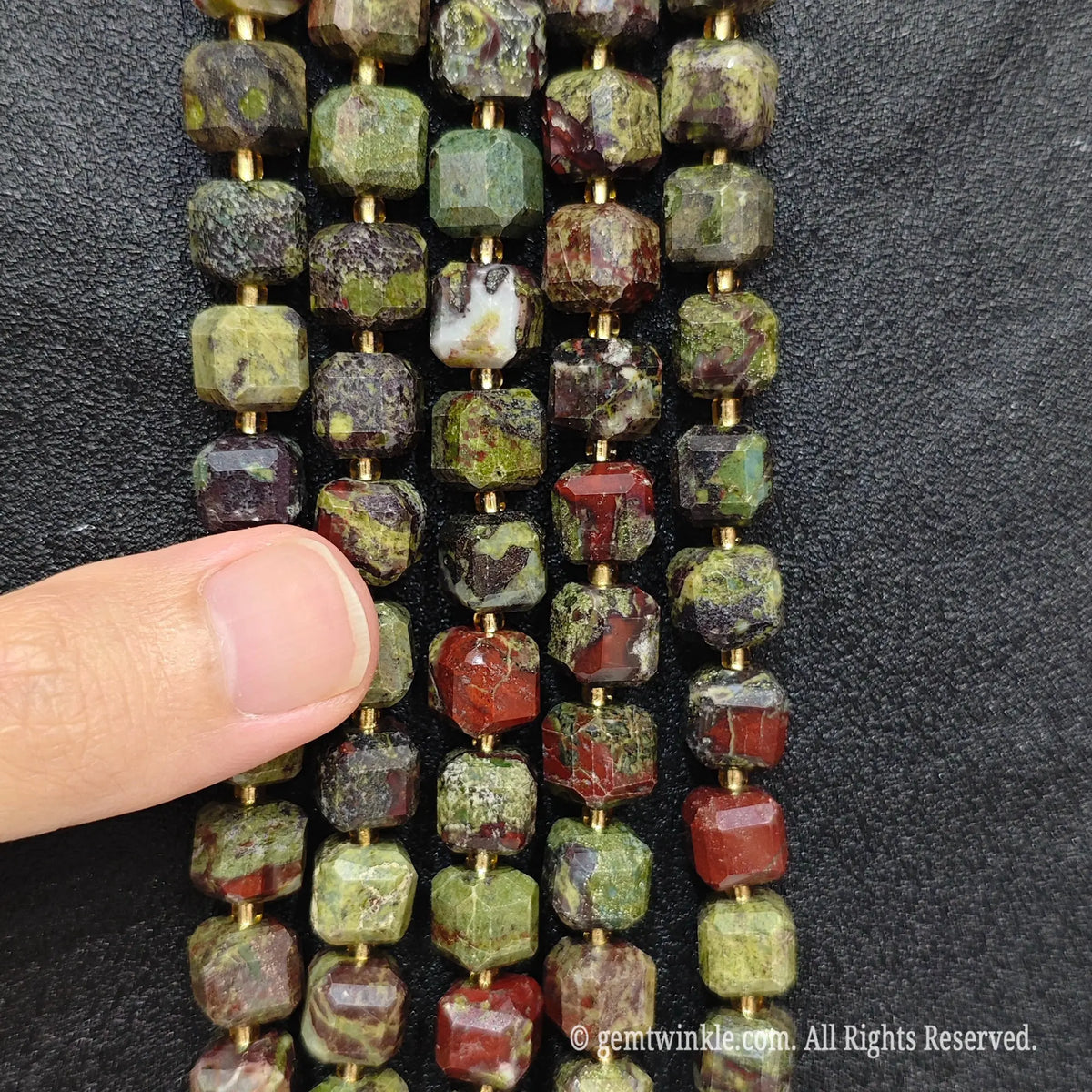 Detailed macro view of natural dragon blood jasper geometric cube beads showcasing red and green matrix patterns