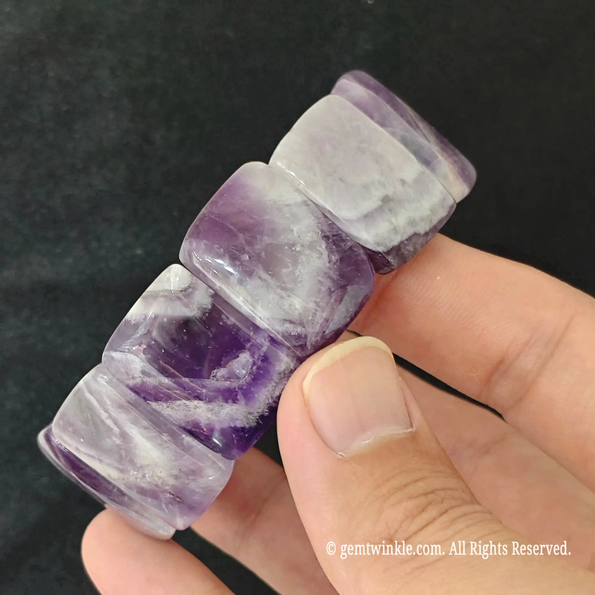 Hand displaying a dreamy chevron amethyst smooth bamboo segment stretch bracelet highlighting V-shaped white quartz banding
