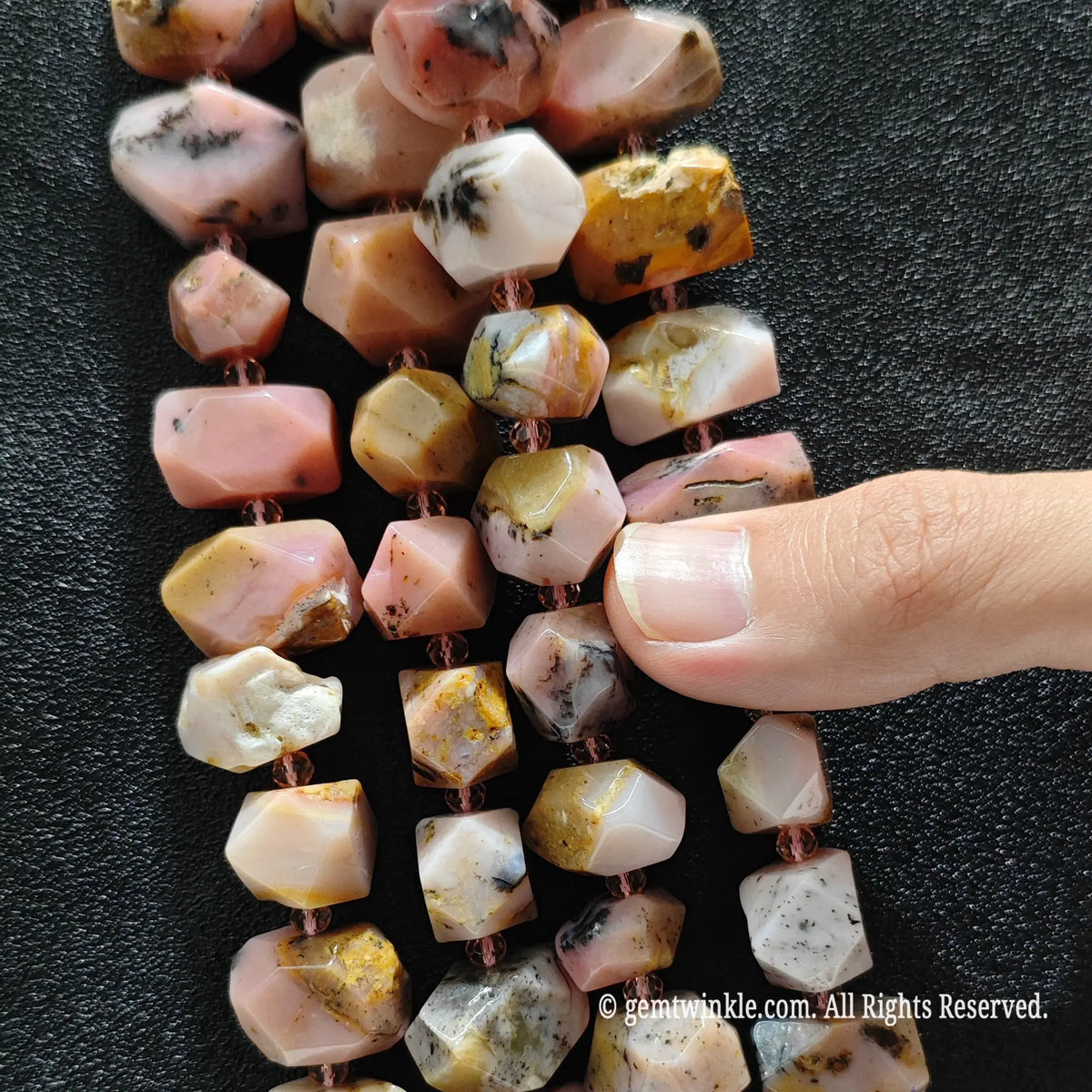 Hand showing large faceted earthy pink opal loose beads highlighting pink yellow color blend and matrix inclusions