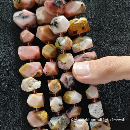 Hand showing large faceted earthy pink opal loose beads highlighting pink yellow color blend and matrix inclusions