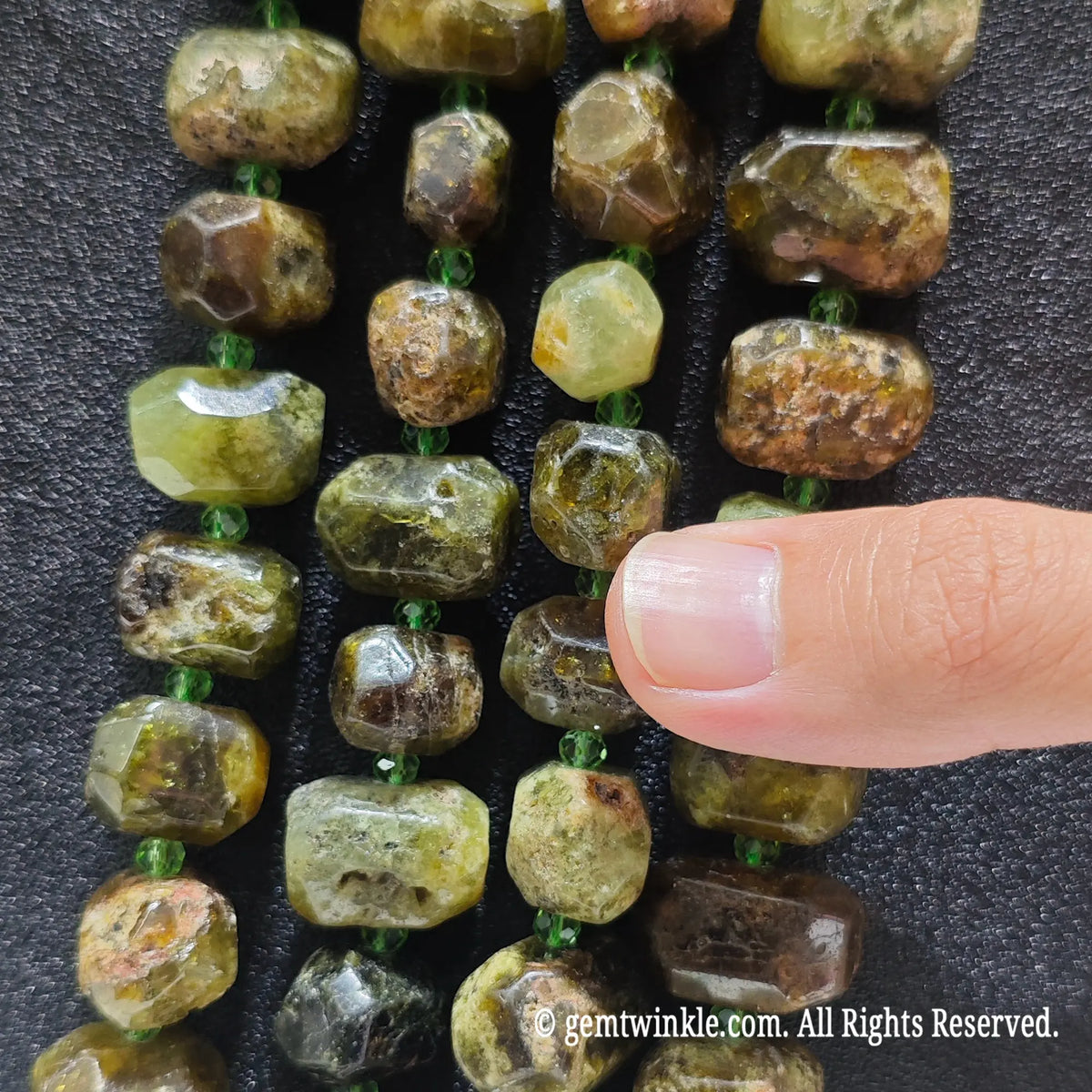 Close up view of natural olive green garnet faceted nugget beads highlighting refractive facets and natural earthy crust