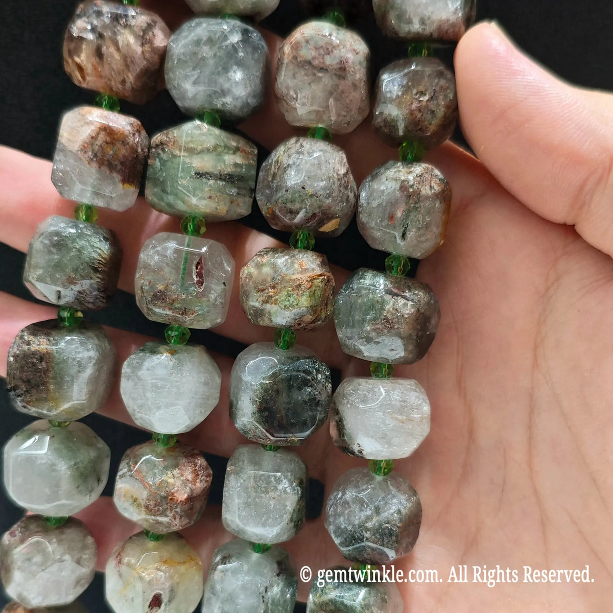 Close up view of natural green phantom quartz faceted cube beads highlighting inner chlorite phantoms and light reflecting facets
