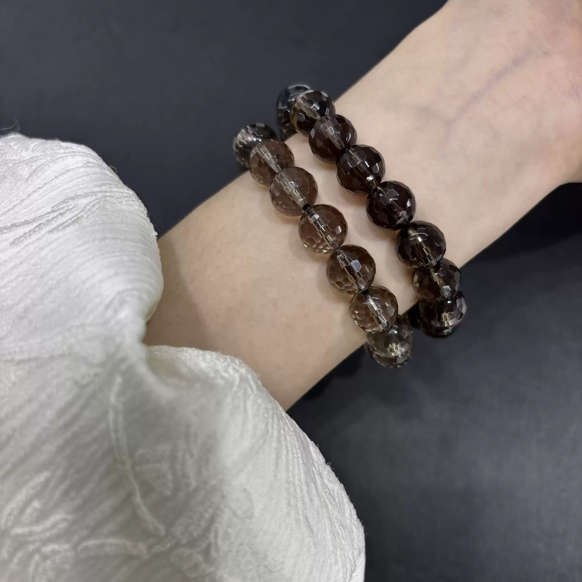 Two smoky quartz faceted bracelets worn on wrist; subtle sparkle from cut surfaces under natural light