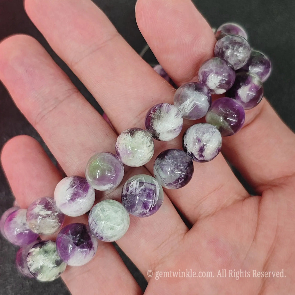 Detailed shot of natural feather fluorite beads demonstrating internal misty veils and smooth polish