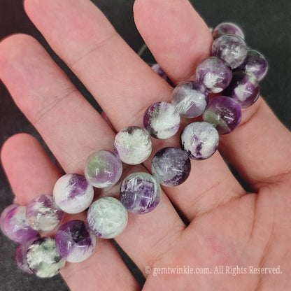 Detailed shot of natural feather fluorite beads demonstrating internal misty veils and smooth polish