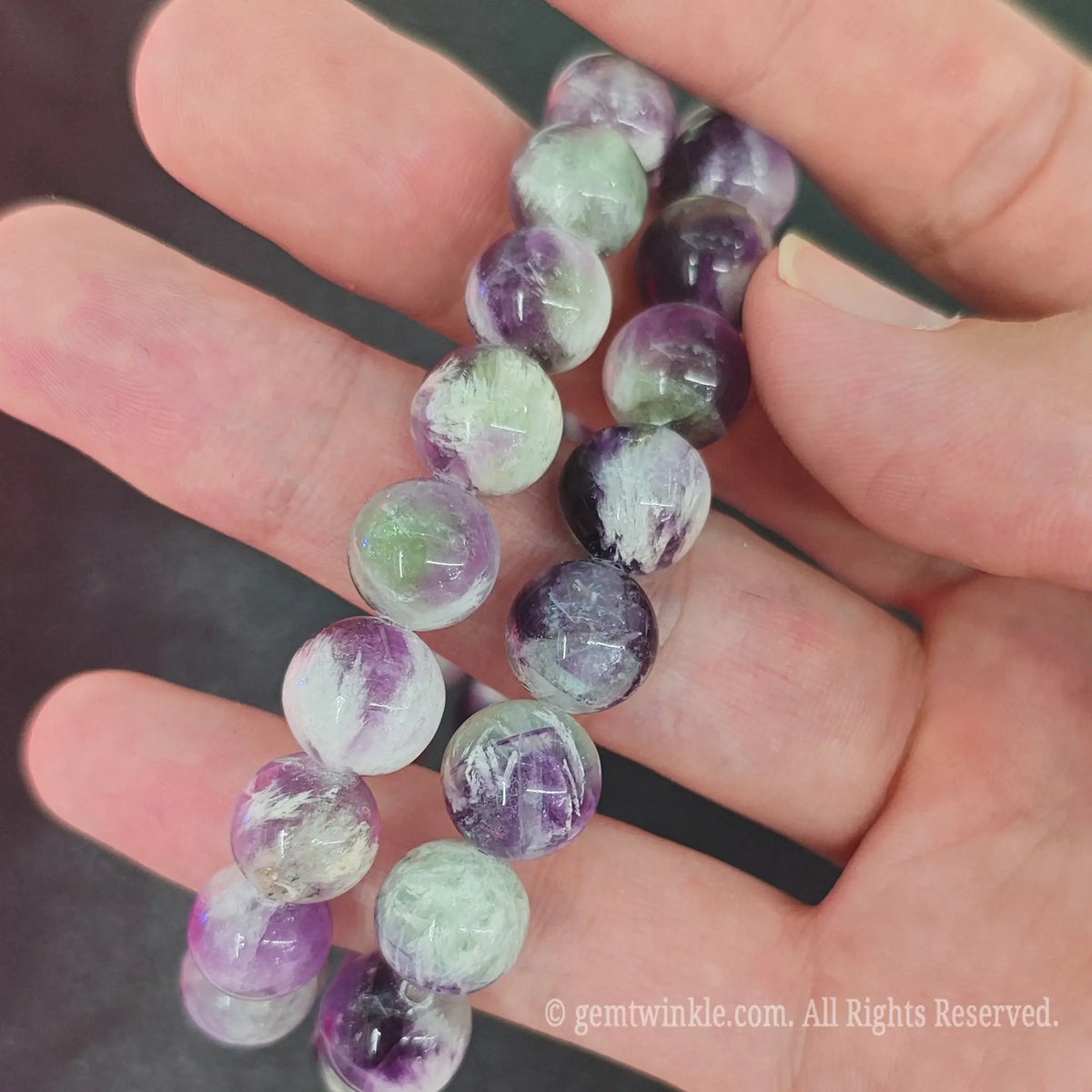 Close up of polished feather fluorite round beads on stretch cord for jewelry making and boutique display
