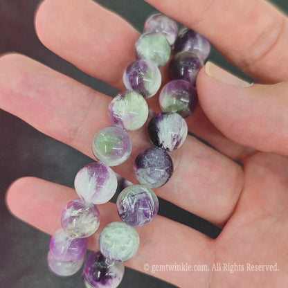 Close up of polished feather fluorite round beads on stretch cord for jewelry making and boutique display