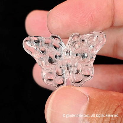 Close up view of translucent clear quartz butterfly carving showing light refraction and raised surface relief details