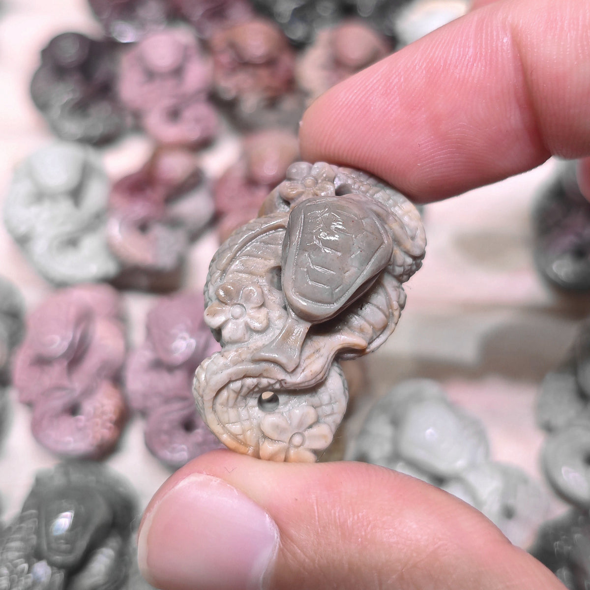 Back view of a flat-laying snake figurine showcasing its smooth polished surface and carved scale patterns