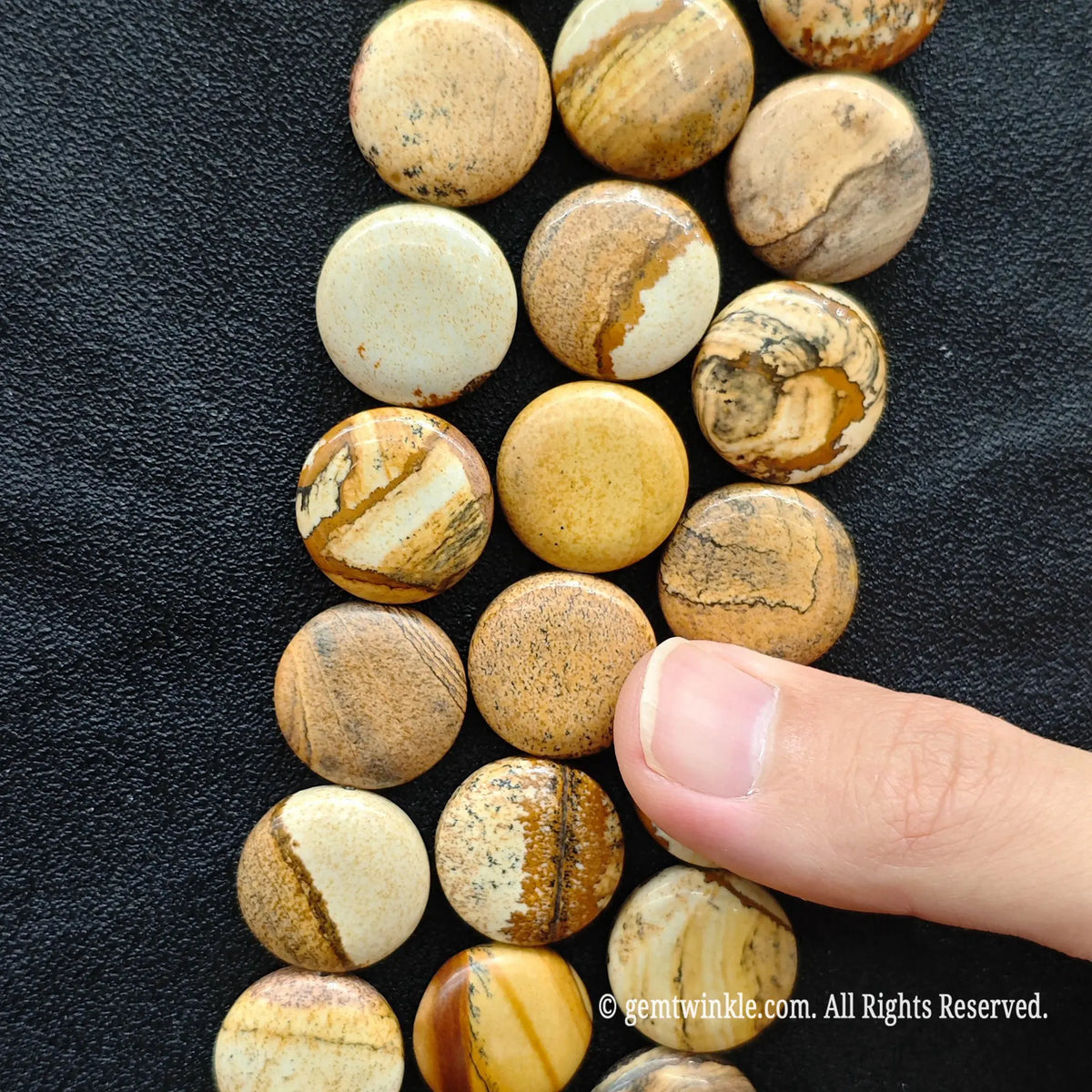 Side view of natural picture jasper coin disc beads strung on loose strands showing sand yellow and ochre brown bands
