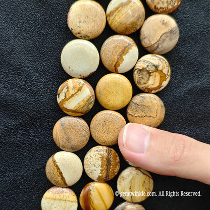 Side view of natural picture jasper coin disc beads strung on loose strands showing sand yellow and ochre brown bands