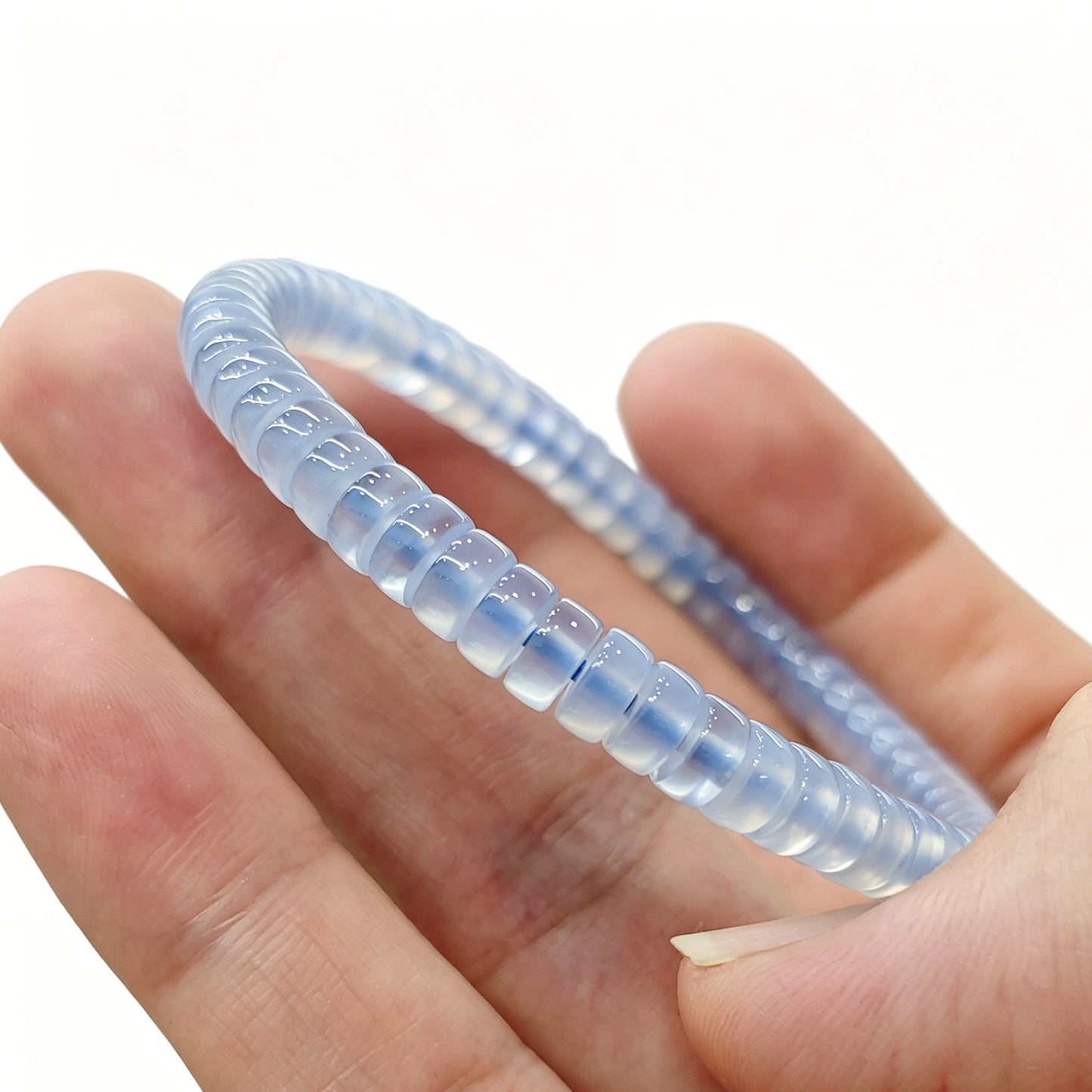 Mini blue agate tablet bracelet gently flexed to demonstrate elasticity and uniform bead alignment