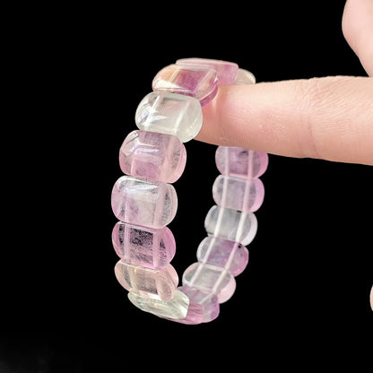 Fluorite bracelet curved in hand, revealing elastic cord construction and smooth bead alignment for comfortable stretch