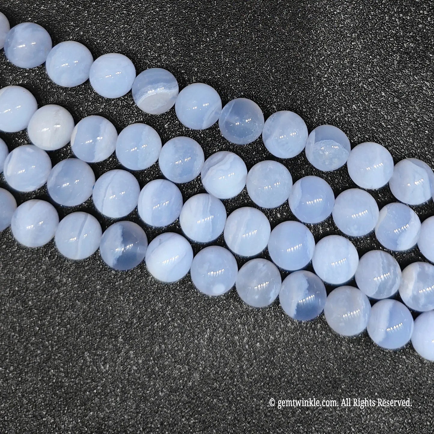 Four clean strands of dyed blue agate crystal beads highlighting surface polish and round cut over an agate base