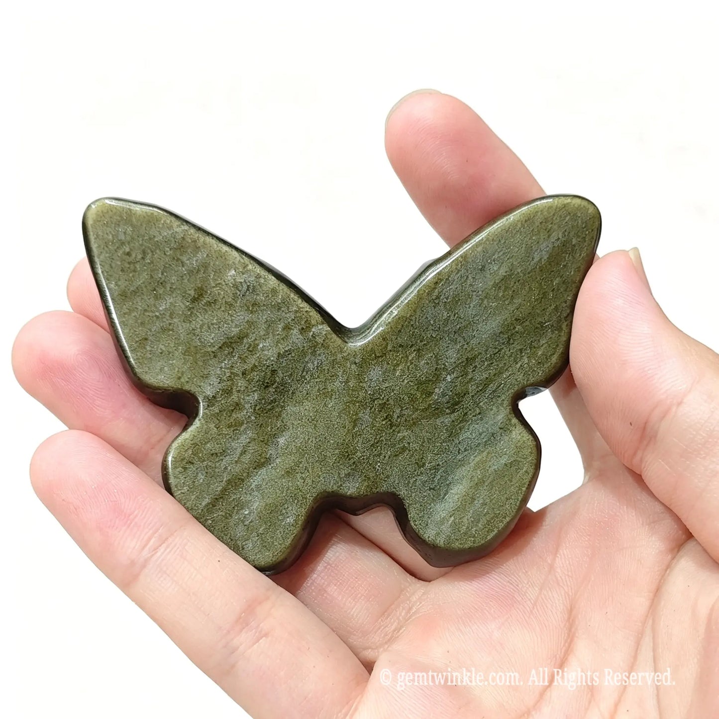 Hand holding gold sheen obsidian moth carving showing flat polished back base for display