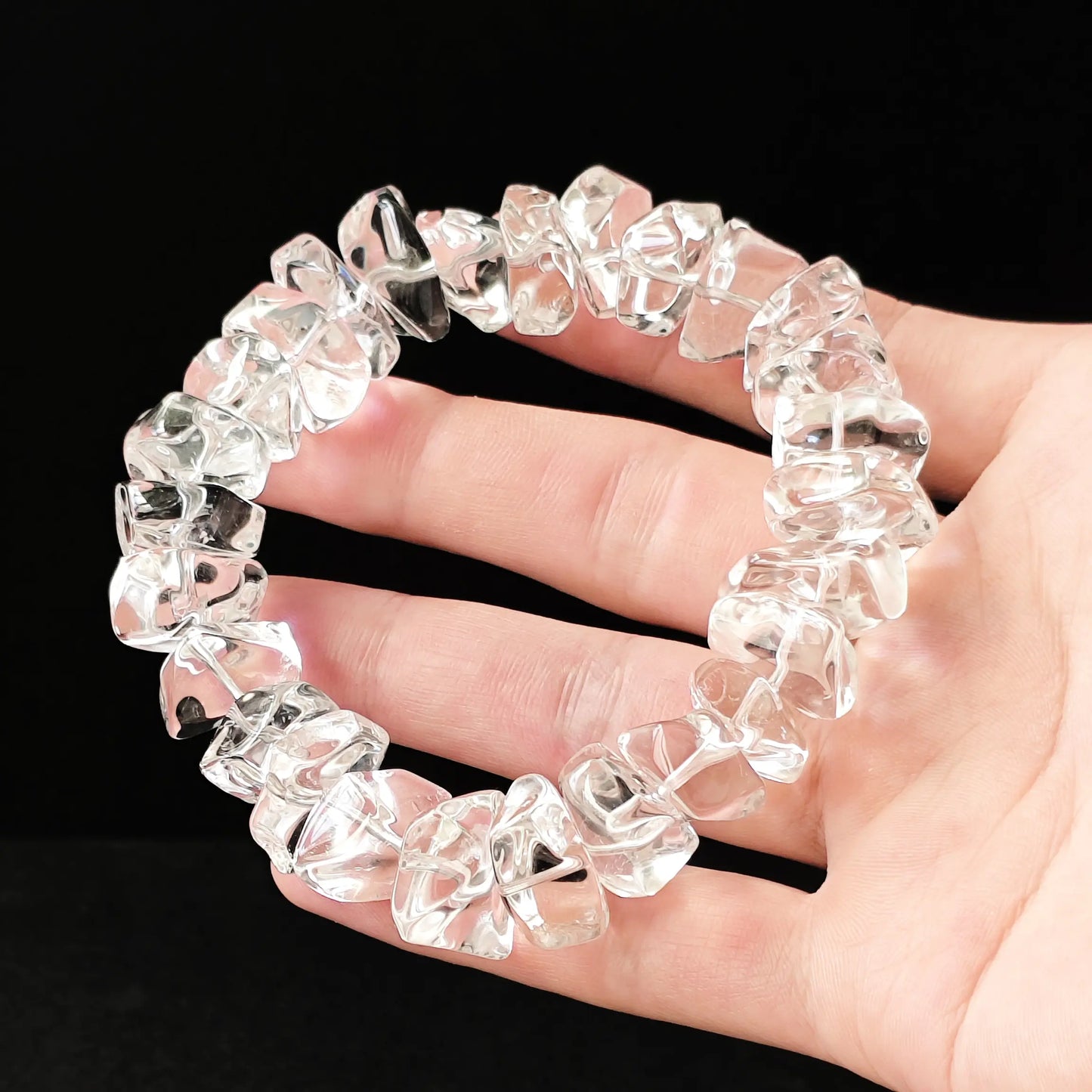 Full-circle view of genuine clear crystal bracelet held in palm; each bead uniquely shaped—no two identical, embodying authentic raw energy flow