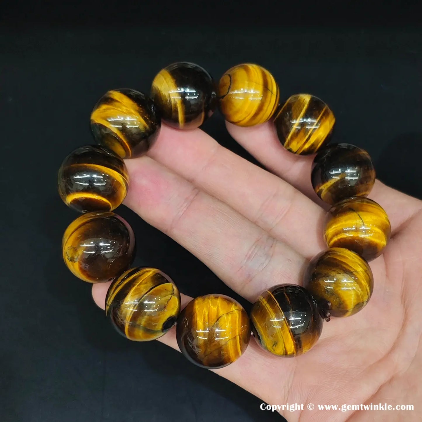 Overhead shot showing the complete bracelet with graduated round beads—demonstrating the full 6mm–20mm size spectrum in one cohesive yellow-banded design.