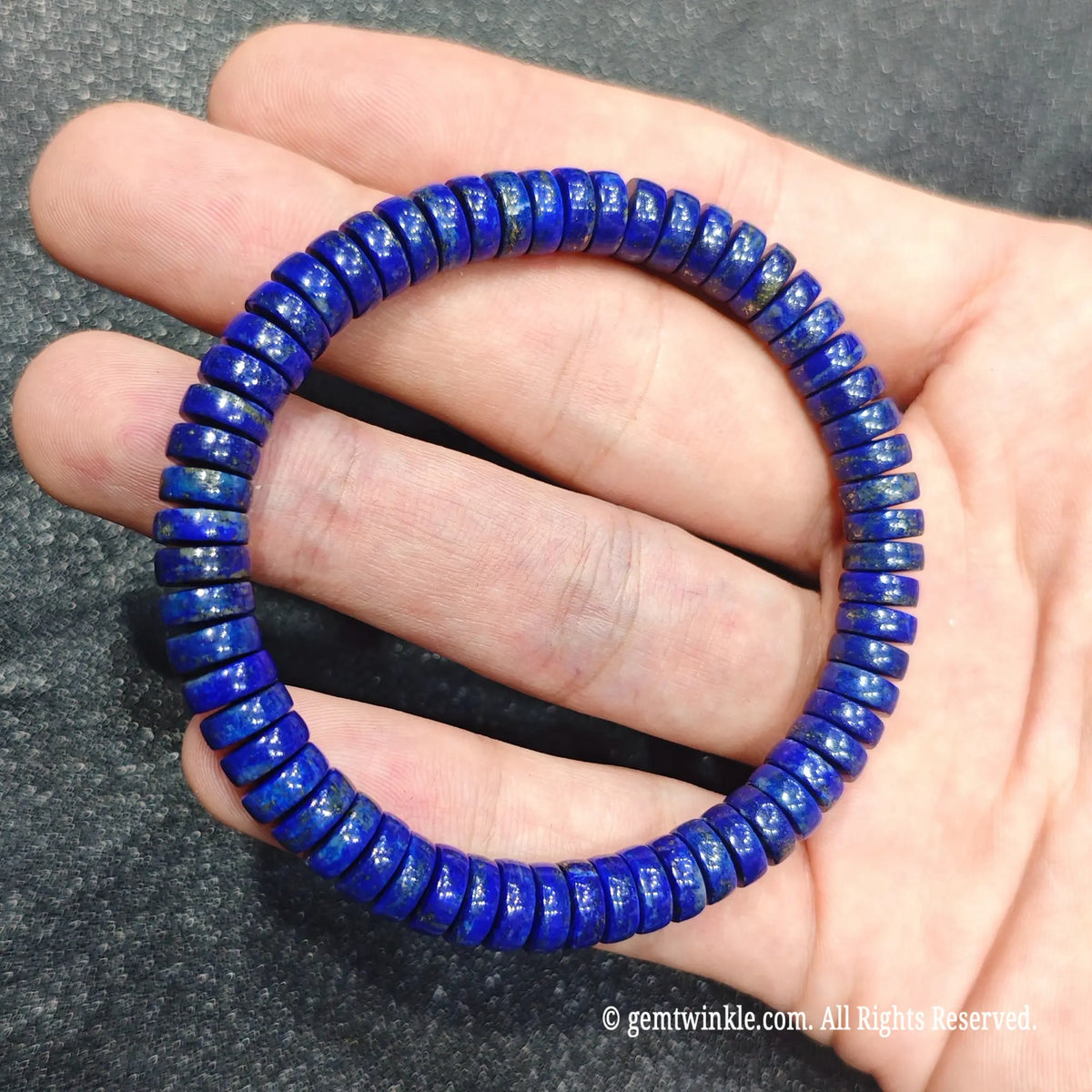 Hand holding a 7x3mm lapis lazuli rondelle bead bracelet showing uniform disc shaping and smooth luster