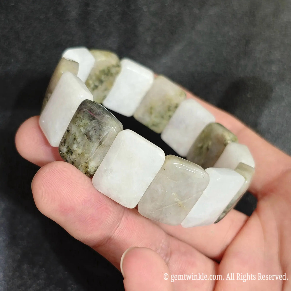 Side view of a natural snowy white golden jadeite quartz smooth segment stretch bracelet showing waxy luster and double row elastic construction
