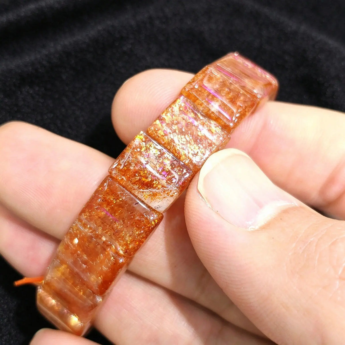Close up view of polished golden sunstone block tile segments showing intense orange red shimmer and smooth curved surfaces