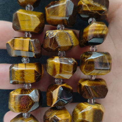 Close up perspective of multiple natural golden tiger eye freeform faceted bead strands showing golden flash