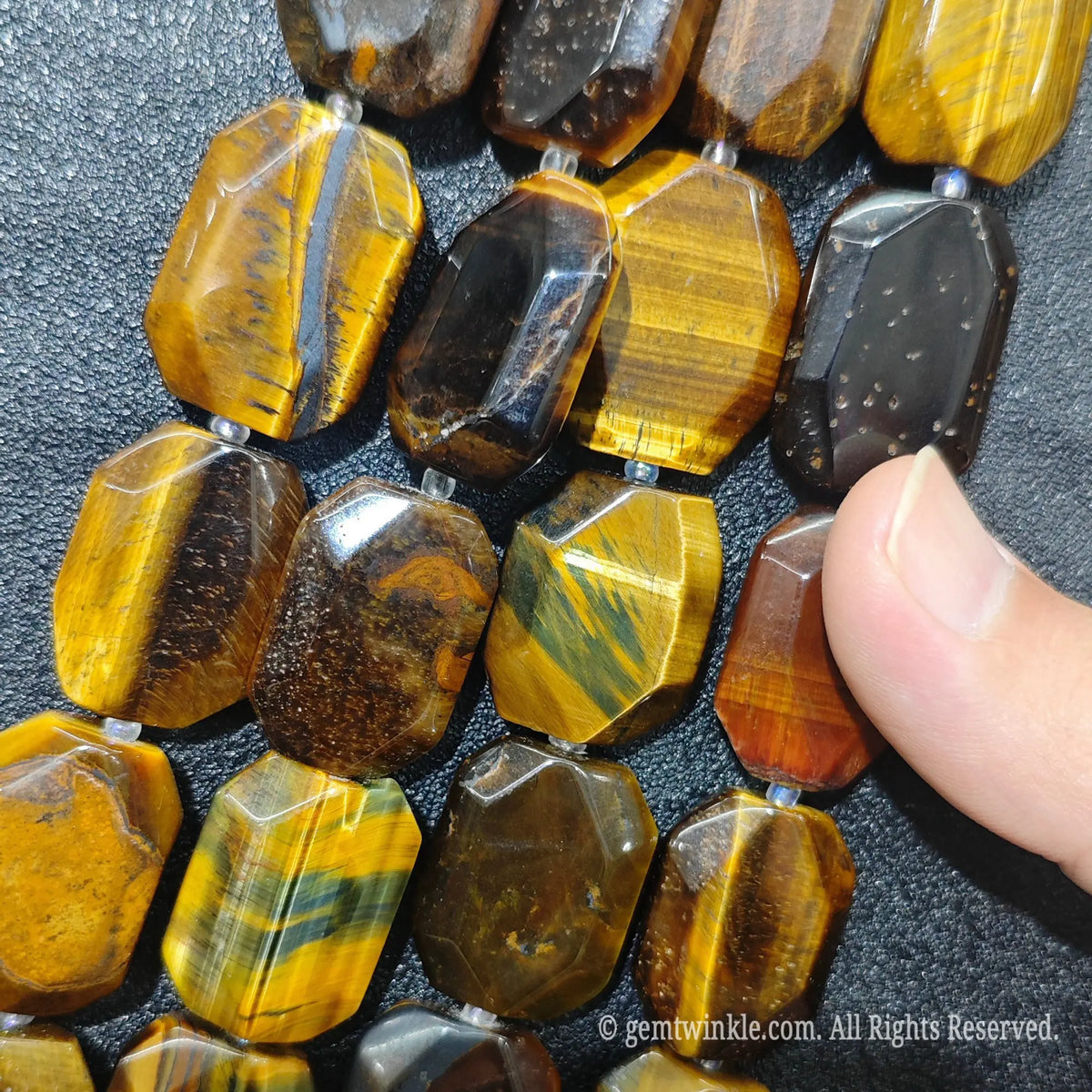 Hand displaying natural golden tiger eye faceted flat slab beads showing rich honey gold color and smooth polished surface