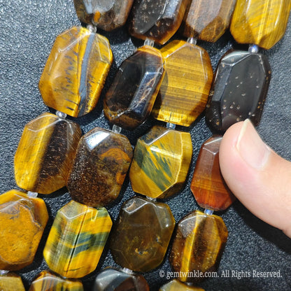 Hand displaying natural golden tiger eye faceted flat slab beads showing rich honey gold color and smooth polished surface