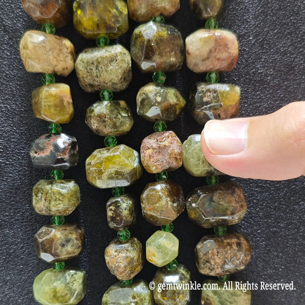 Hand displaying natural green garnet faceted freeform beads showing olive moss green colors and pre-drilled center holes