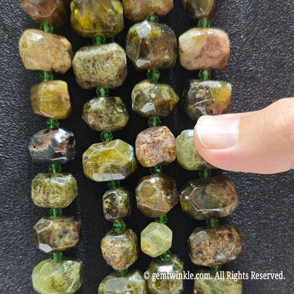 Hand displaying natural green garnet faceted freeform beads showing olive moss green colors and pre-drilled center holes