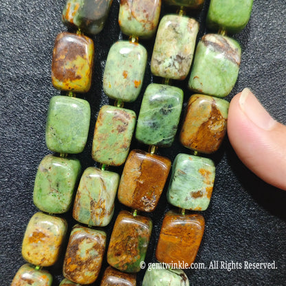 Finger pointing to 17x12mm green jasper pillar beads showcasing smooth polished surface and centered drill hole