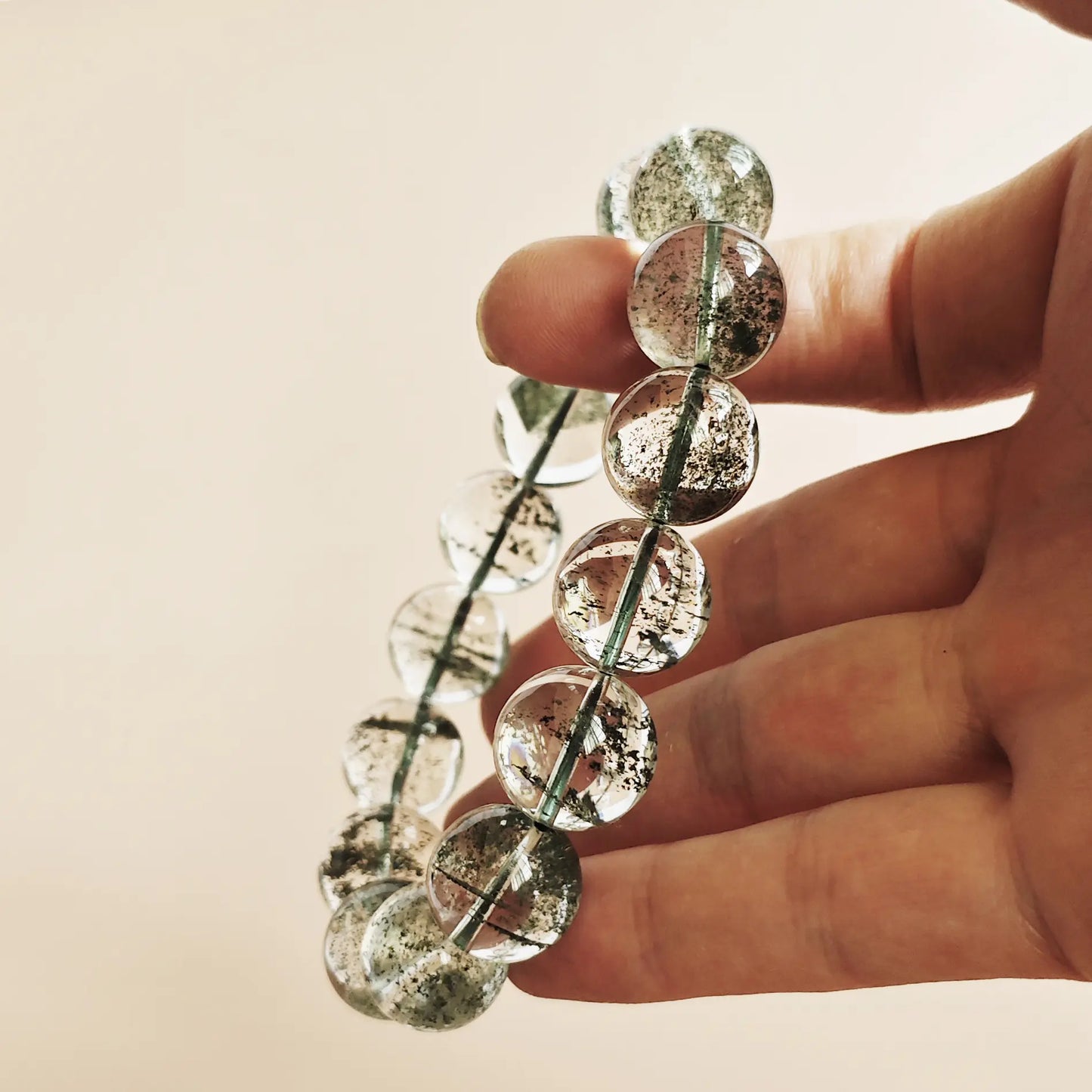 Green phantom quartz bracelet stretched between fingers—demonstrating durable elastic cord and secure knotting, all-green internal structure