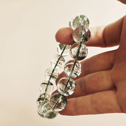 Green phantom quartz bracelet stretched between fingers—demonstrating durable elastic cord and secure knotting, all-green internal structure