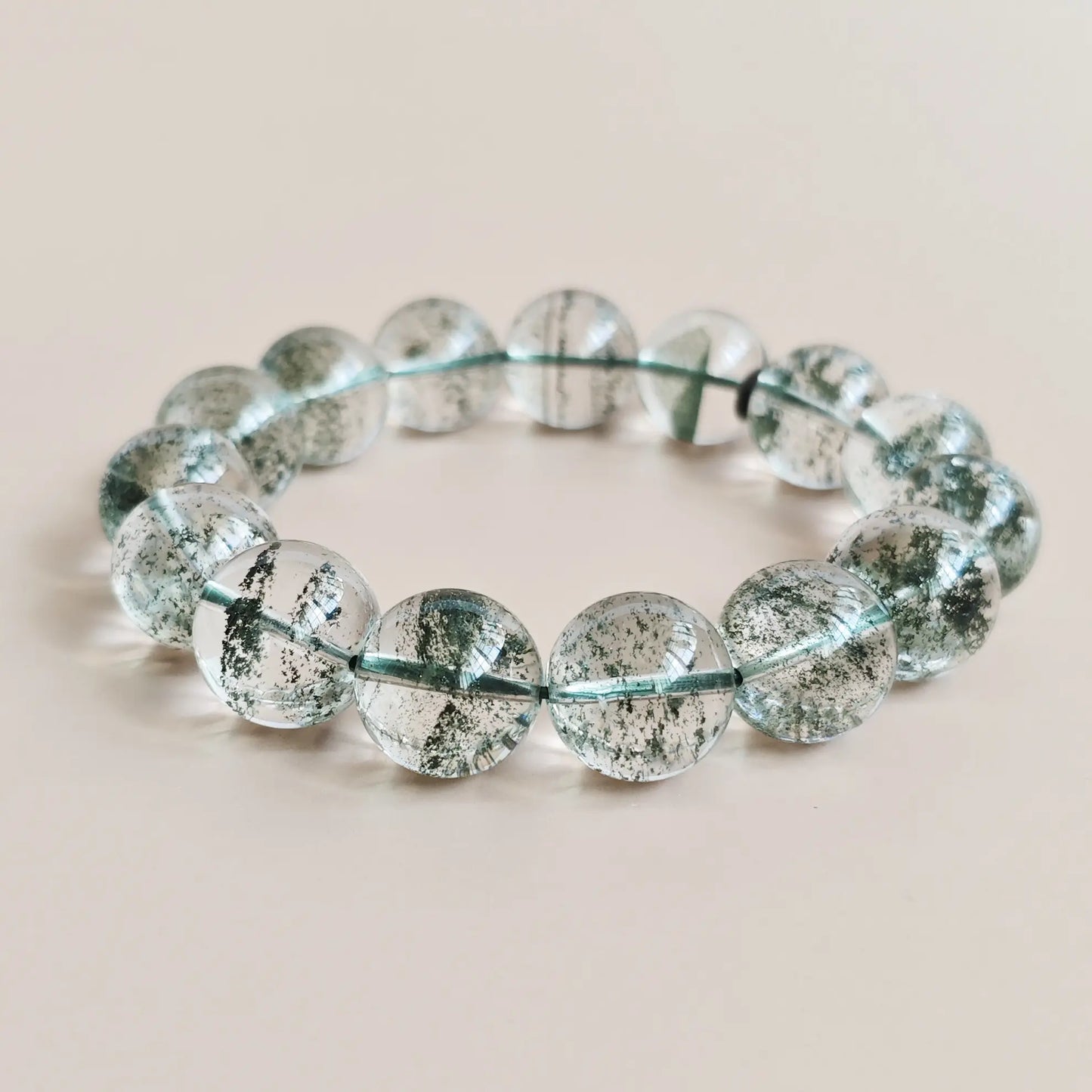 Natural green phantom quartz beads, ~15mm, with vivid layered green inclusions in clear crystal—stretch elastic, displayed flat
