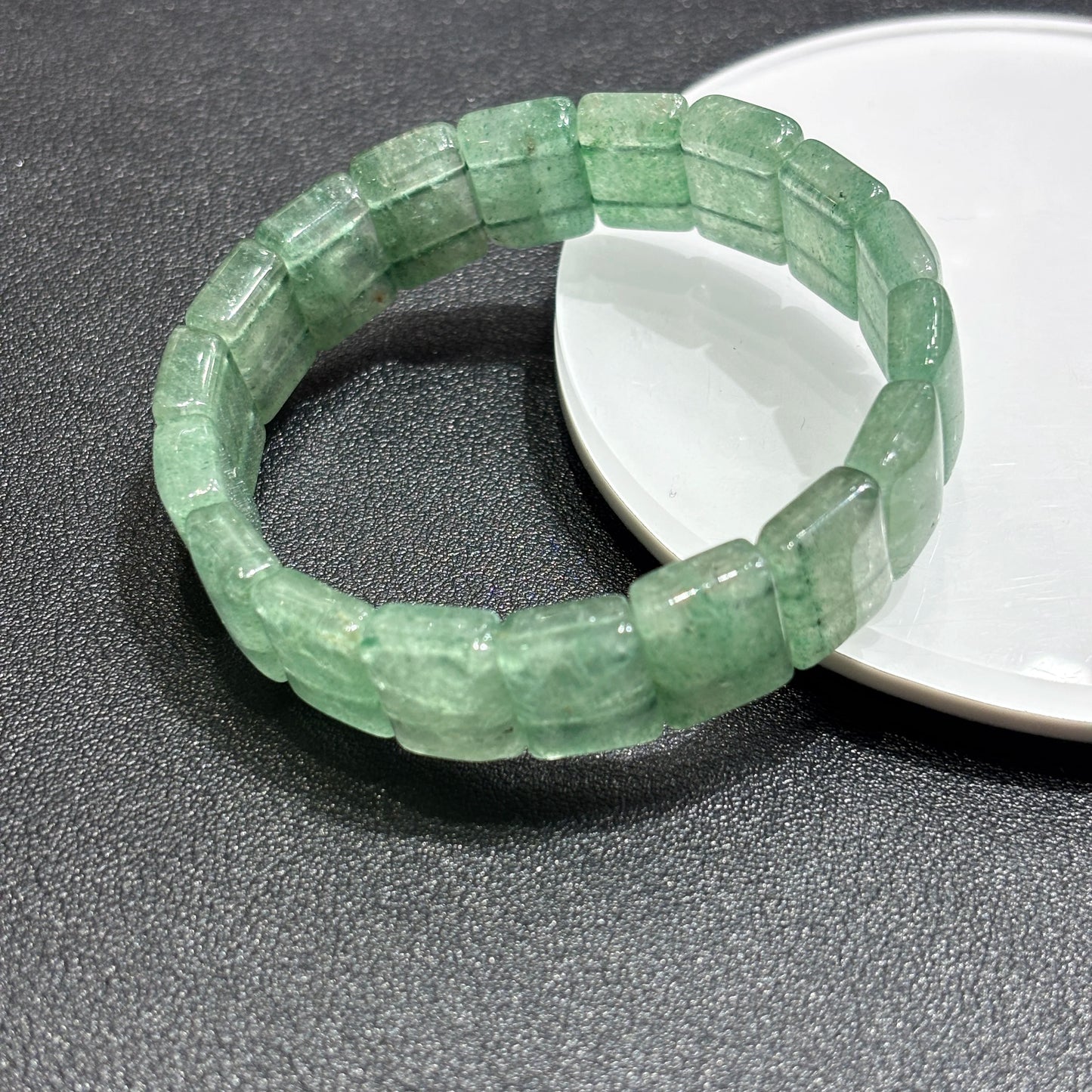 Close-up of natural green strawberry quartz tablet bead revealing soft green color and gentle white inclusions; evokes balanced intention