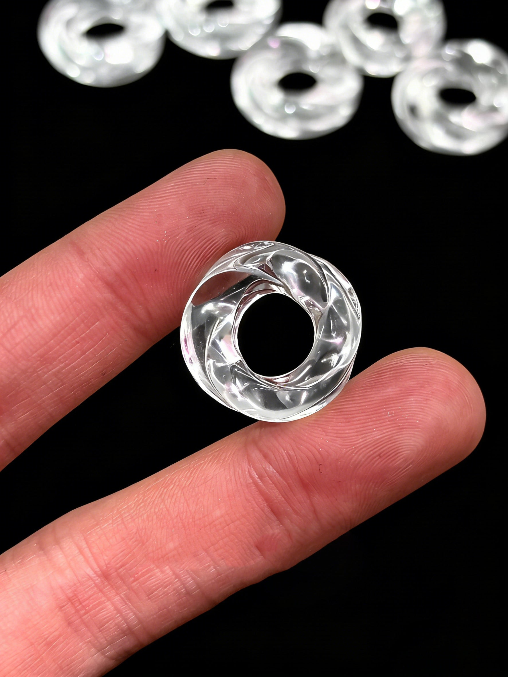 Hand holding clear quartz Möbius ring pendant, demonstrating 3–4mm thickness and central opening for chain threading