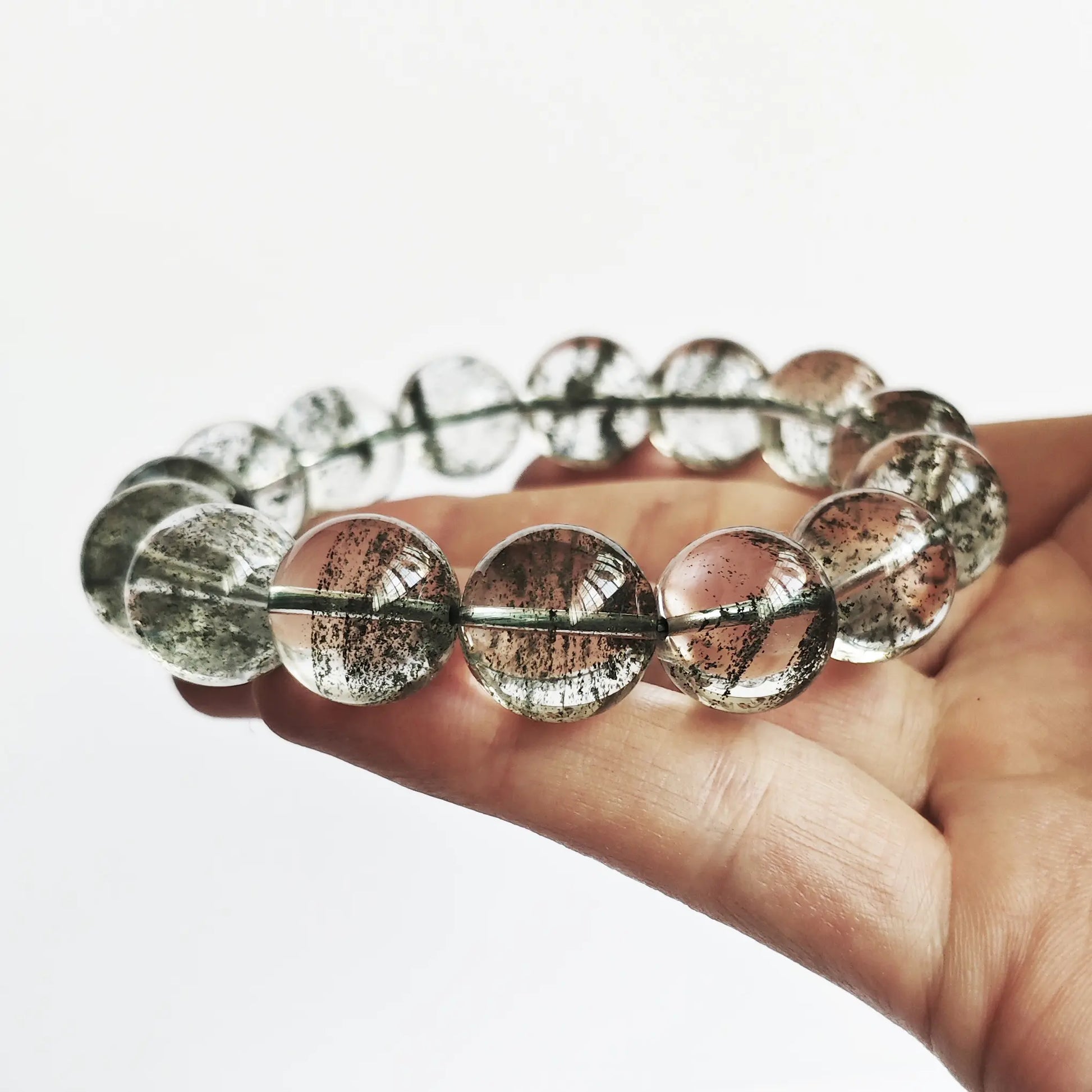 Men’s green phantom quartz bracelet held in palm—showing uniform green layers, clarity, and bead size under neutral light