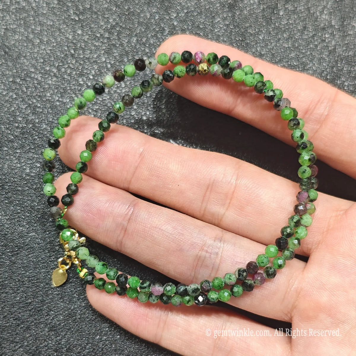Close up of 3mm Ruby in Zoisite beads looped on hand highlighting gold-plated lobster clasp and extender