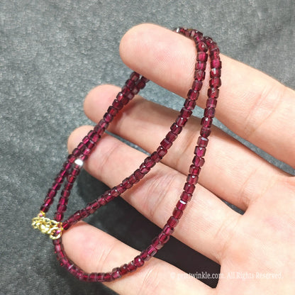 Close up of 3mm Red Garnet square beads looped on hand highlighting gold-plated lobster clasp and extender