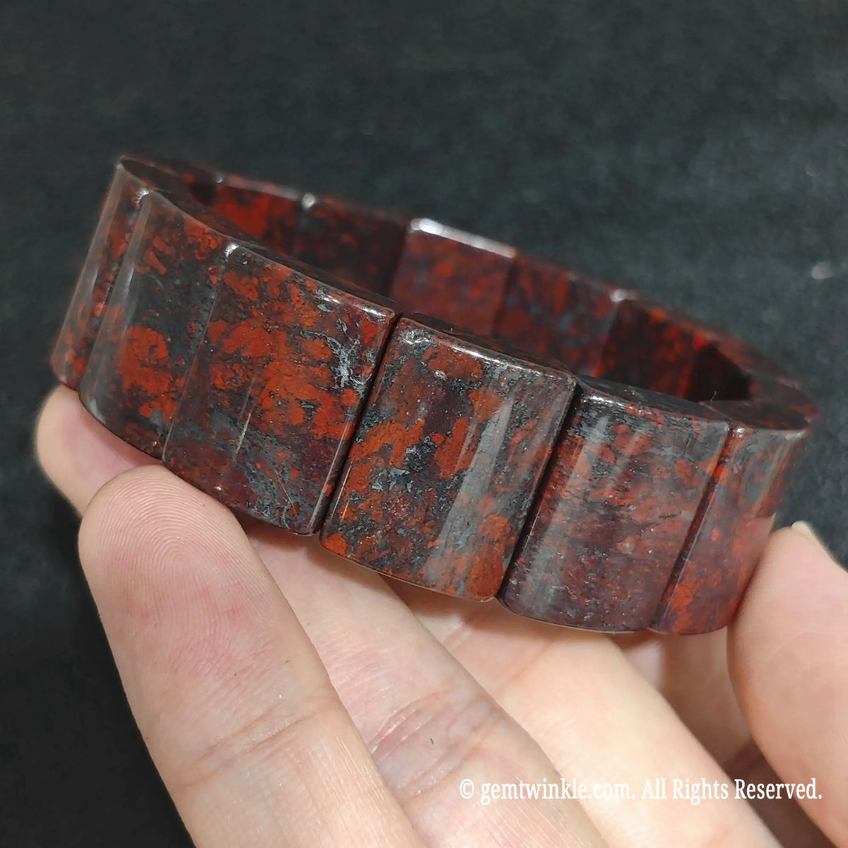 Angled view of a large curved bloodstone gemstone bracelet highlighting its polished domed finish
