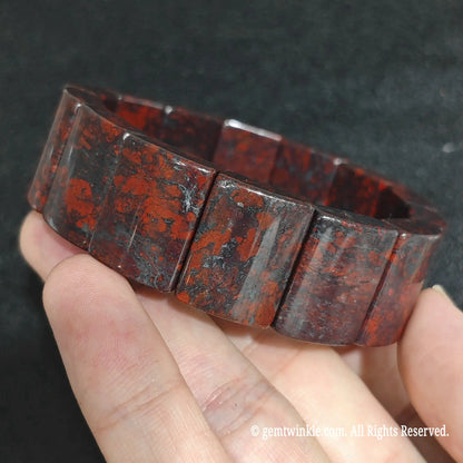 Angled view of a large curved bloodstone gemstone bracelet highlighting its polished domed finish