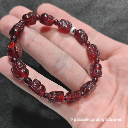 Top view of garnet pi yao carving charm strand showing intricate miniature mythical creature beads on hand
