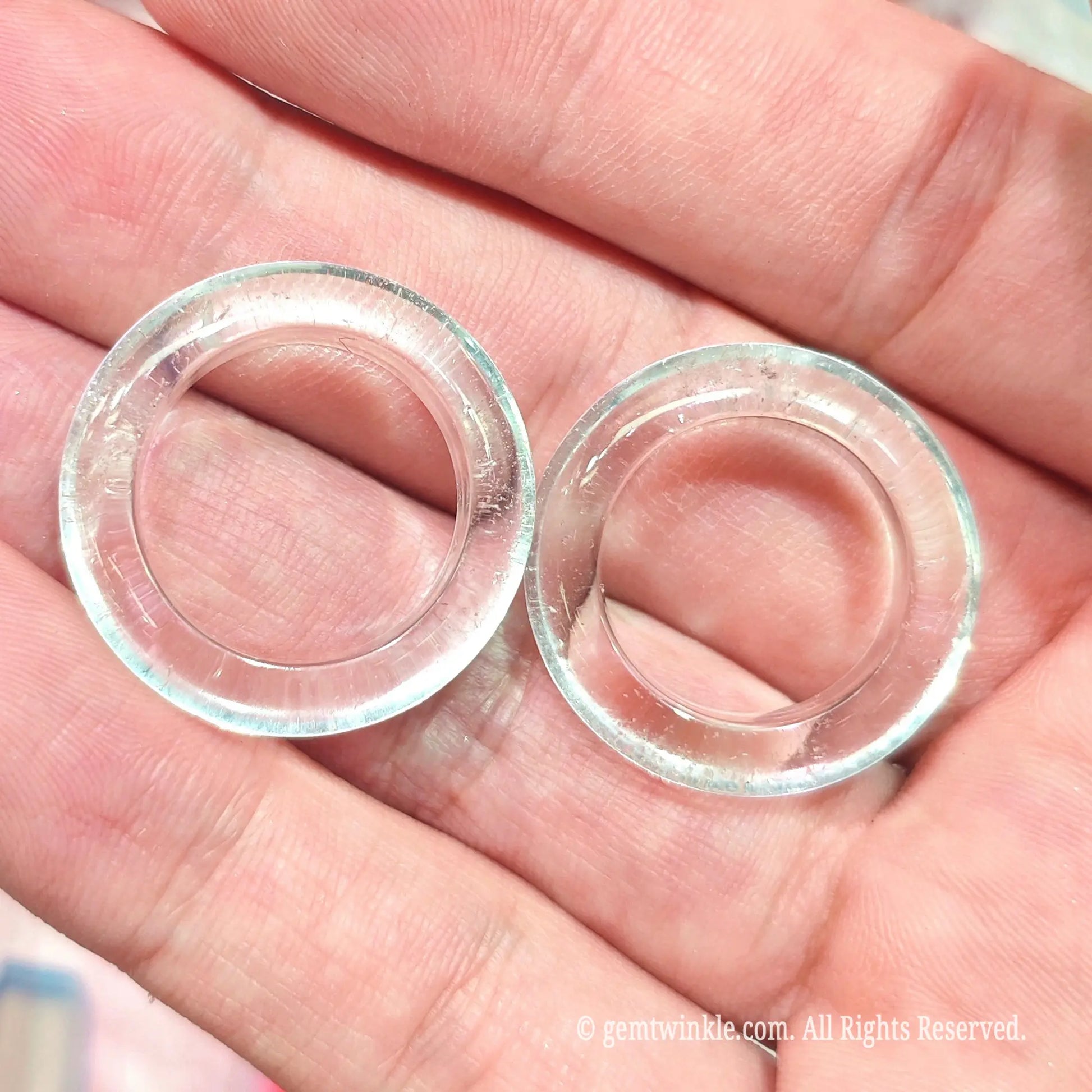 Top view of two solid clear quartz crystal finger rings in hand displaying 16mm to 19mm inner diameter shapes