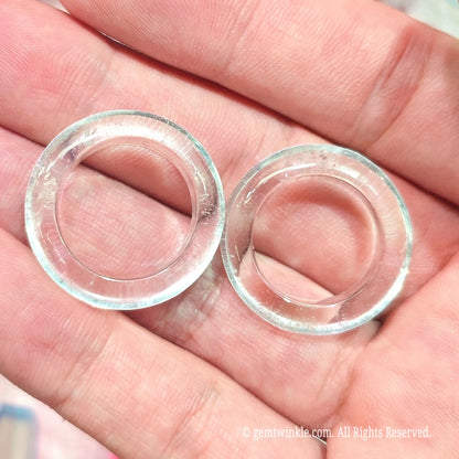 Top view of two solid clear quartz crystal finger rings in hand displaying 16mm to 19mm inner diameter shapes