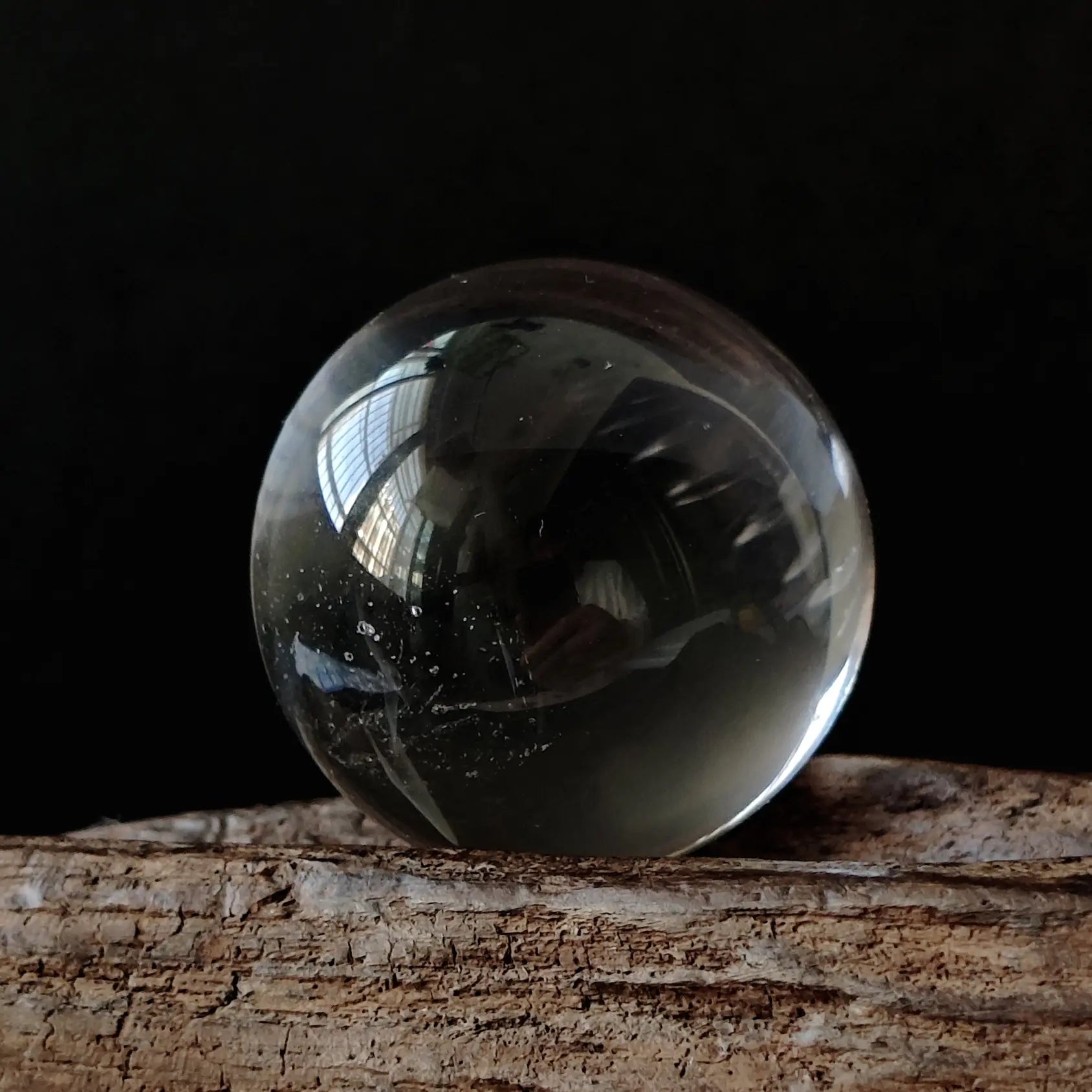 Natural clear quartz sphere (~2cm), highly transparent with glassy luster, resting on a small resin base; premium crystal desk decor for mindful spaces