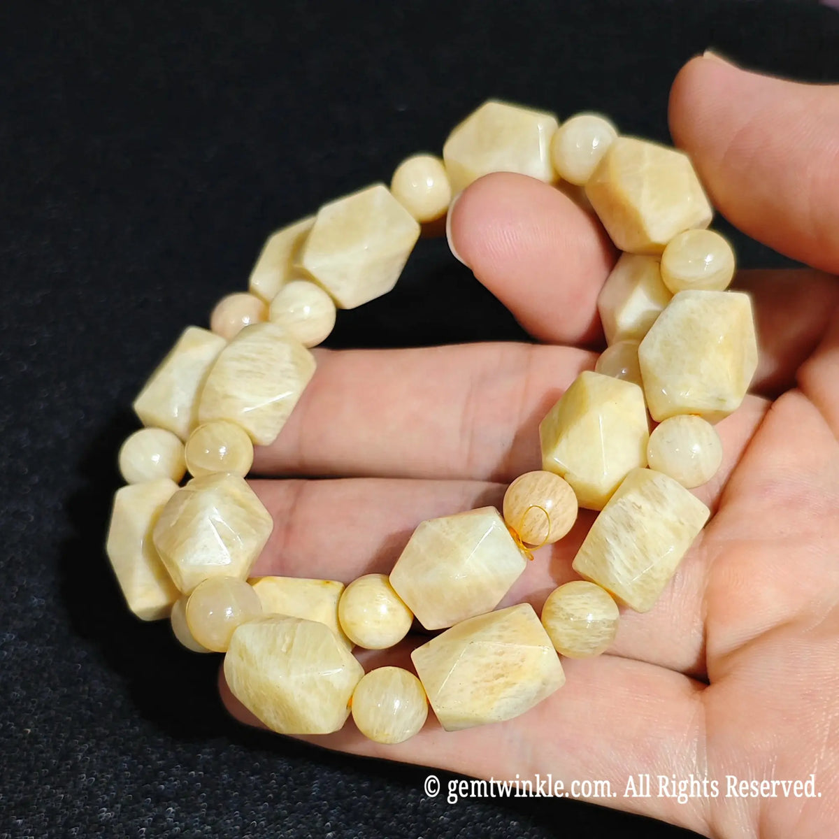 Hand displaying natural yellow quartzite faceted freeform stretch bracelets highlighting smooth waxy luster