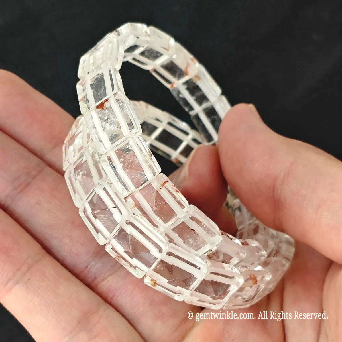 Hand displaying a clear quartz pyramid faceted tile stretch bracelet highlighting transparent crystal reflections under light